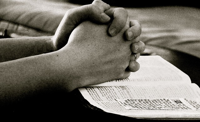 Hands folded in prayer over a bible.